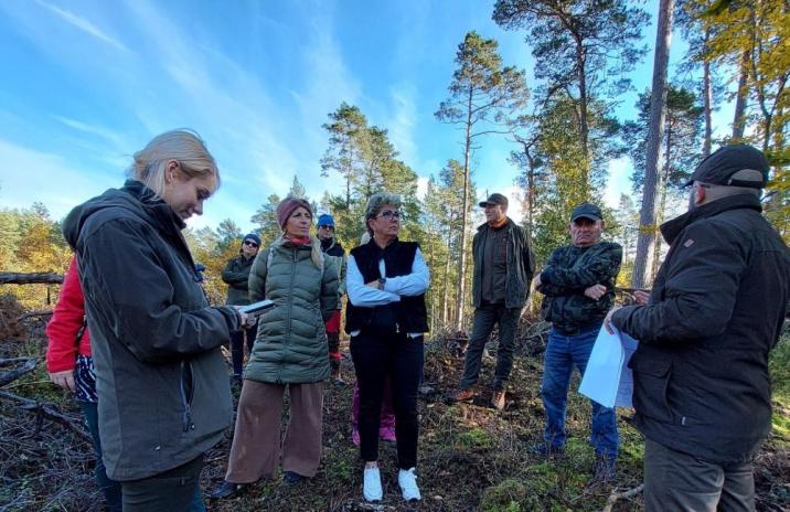 zdjęcie przedstawia osoby stojące w lesie, prowadzące rozmowę